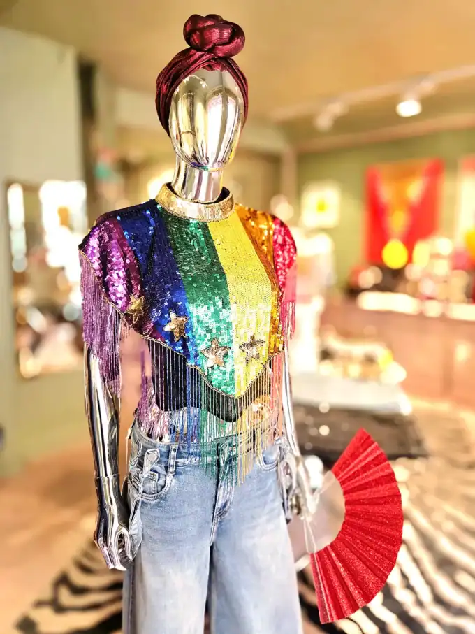 Farverig perlekappe med Pride-tema på mannequin.