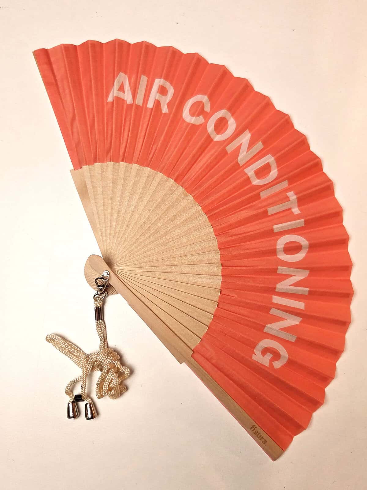 Håndvifte i træ, med teksten AIRCONDITIONING på peach baggrund, fra fisura
