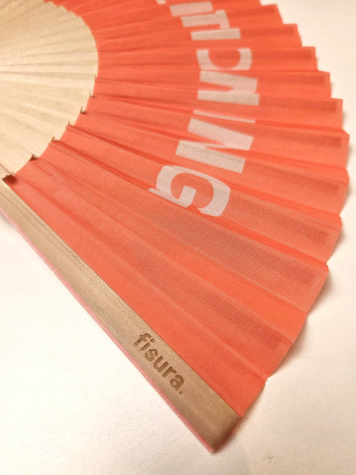 Håndvifte i træ, med teksten AIRCONDITIONING på peach baggrund, fra fisura - detaljer