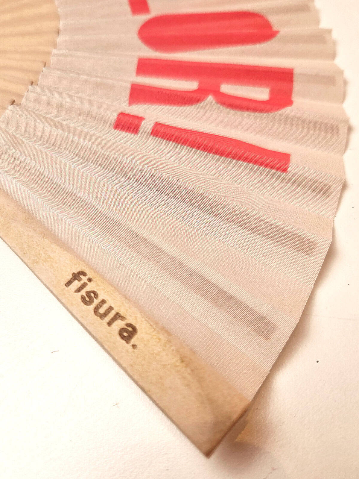 Håndvifte i træ med teksten QUE CALOR i rød, fra fisura - detaljer