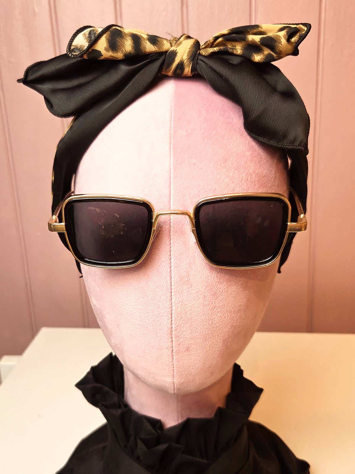 Solbriller med bred guldkant og mørke glas