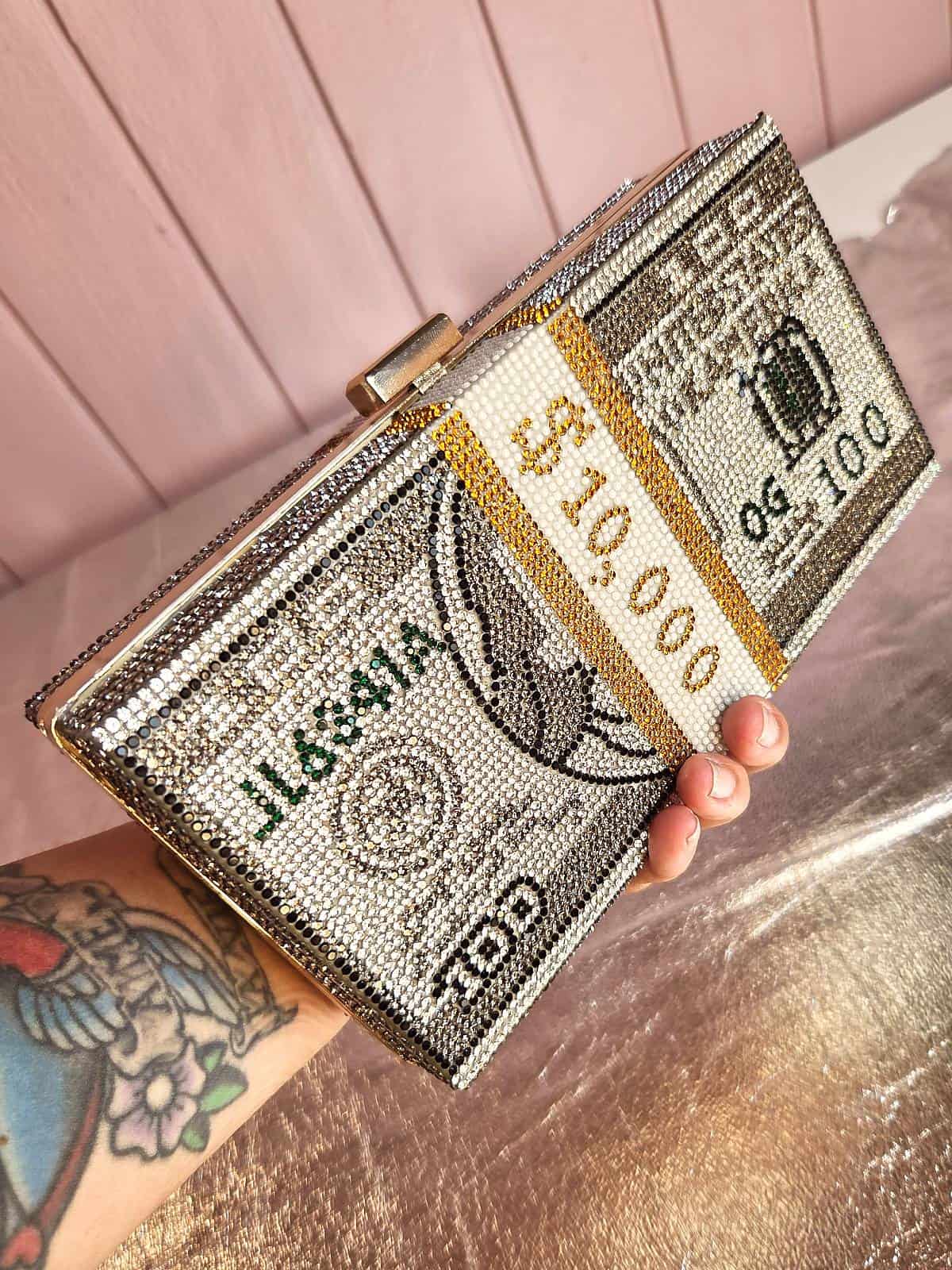 clutch med similisten formet som dollarbundt holdt i hånd