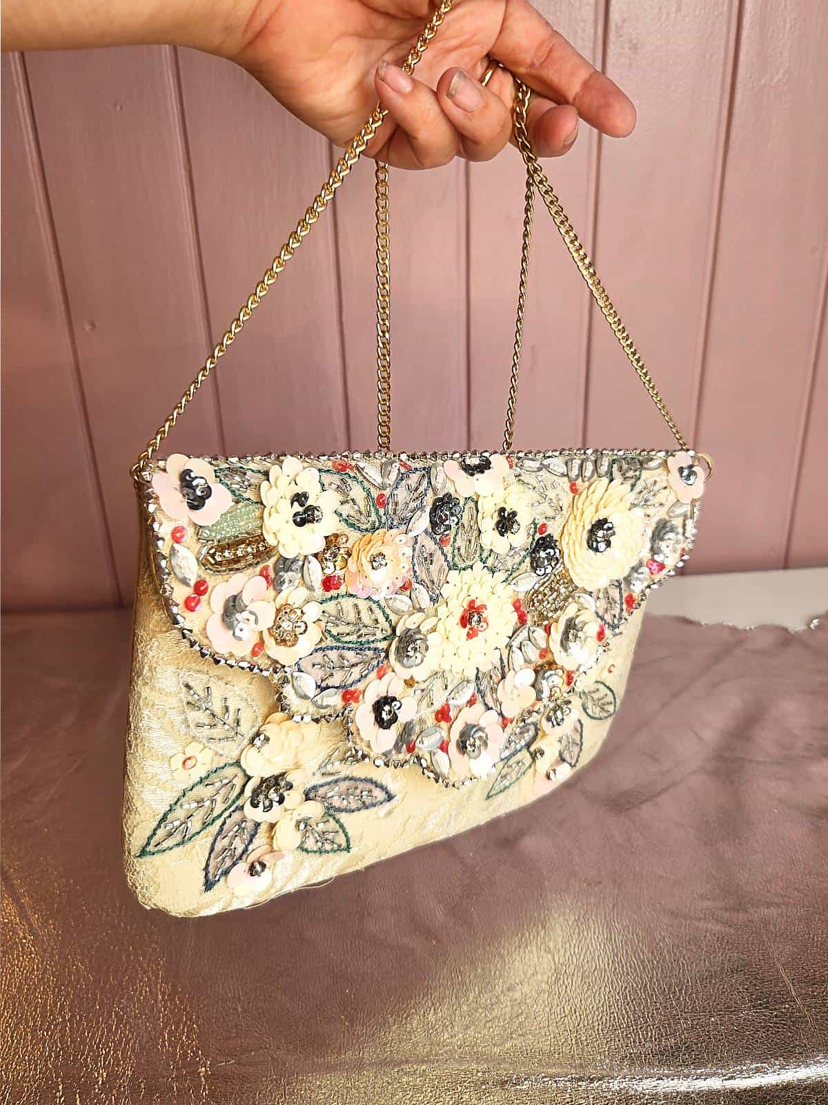 håndlavet perleclutch med blomster hængende i hånd