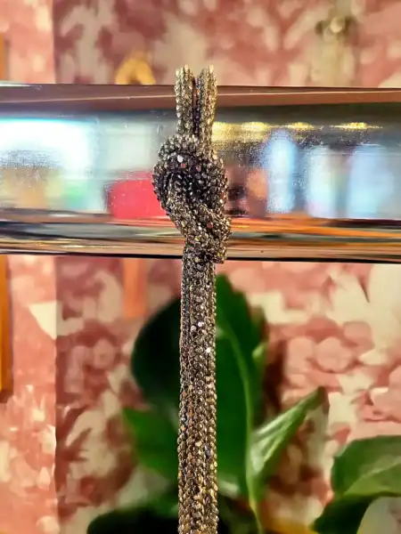 Elegant diamantbesat slangesmykke hængende på metalstang.