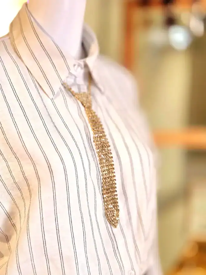 Elegant guld halskæde kombineret med similislips til et sofistikeret look.