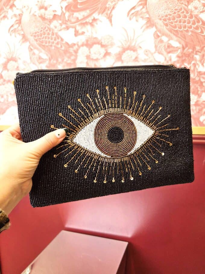 Evil Eye clutch i sort med orange detaljer og øje-design, perfekt til tilbehør og beskyttelse.
