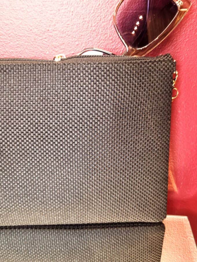 Sort clutch med orange Evil Eye-symbol og elegant design.