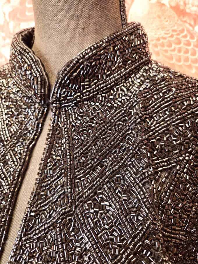 Sort zigzagperlekappe med detaljerede perler og elegant design.