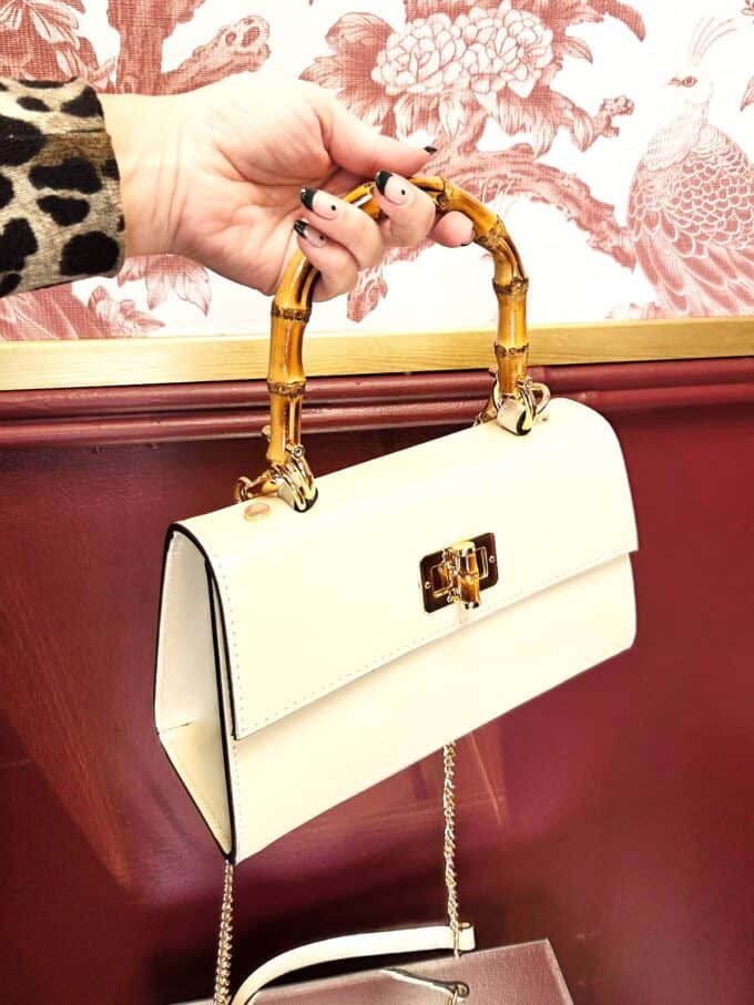 Elegant cremefarvet læderclutch med bambushank og guldfarvet lås.