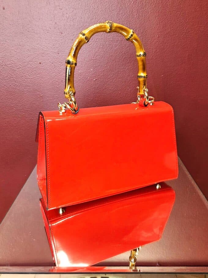 Clutch i læder med bambushank i cremefarvet design, perfekt til elegante anledninger.