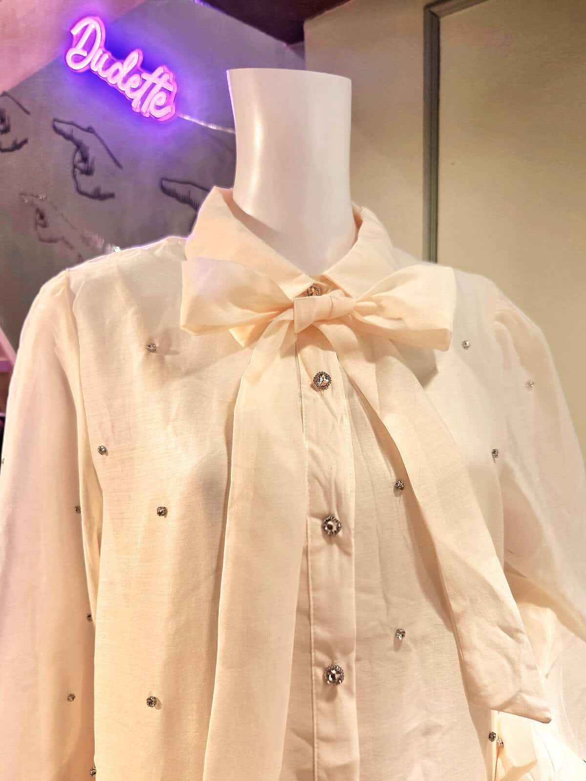 Hvid kjole med similiperler og bow-tie detalje, perfekt til festlige anledninger.