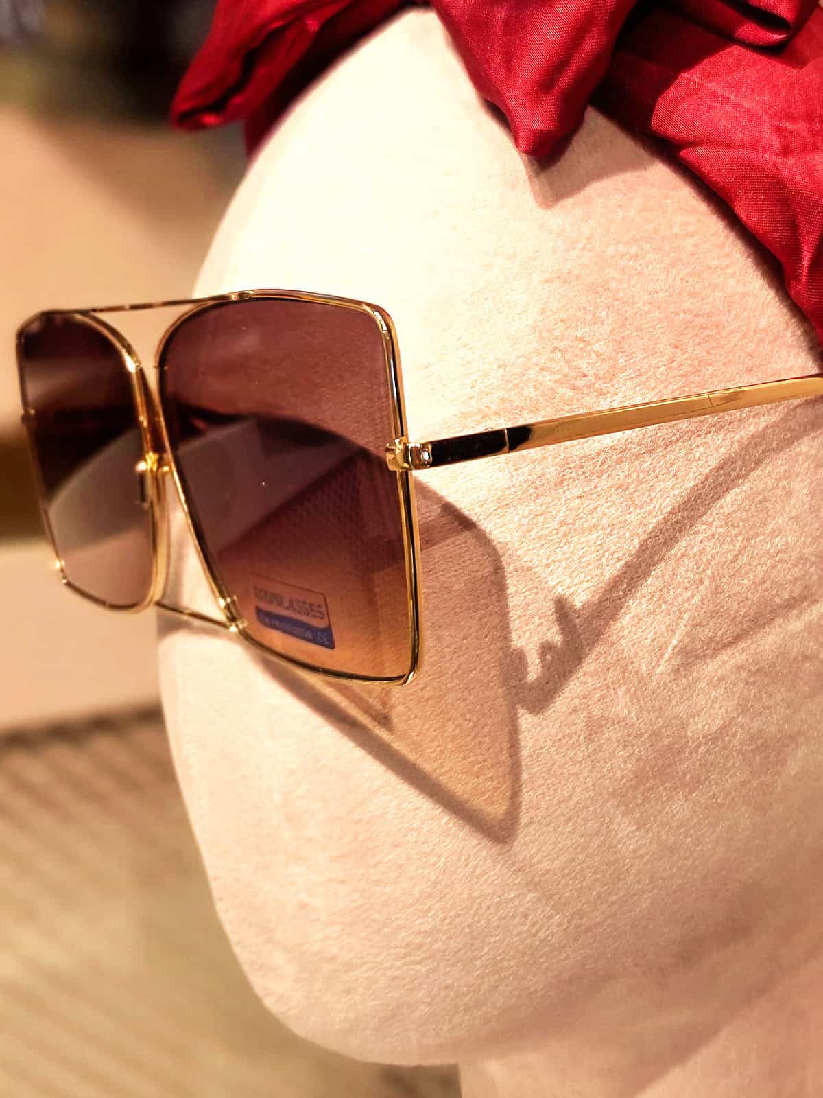 Solbriller med guldramme og brune linser, stilfuldt tilbehør til sommeroutfit.
