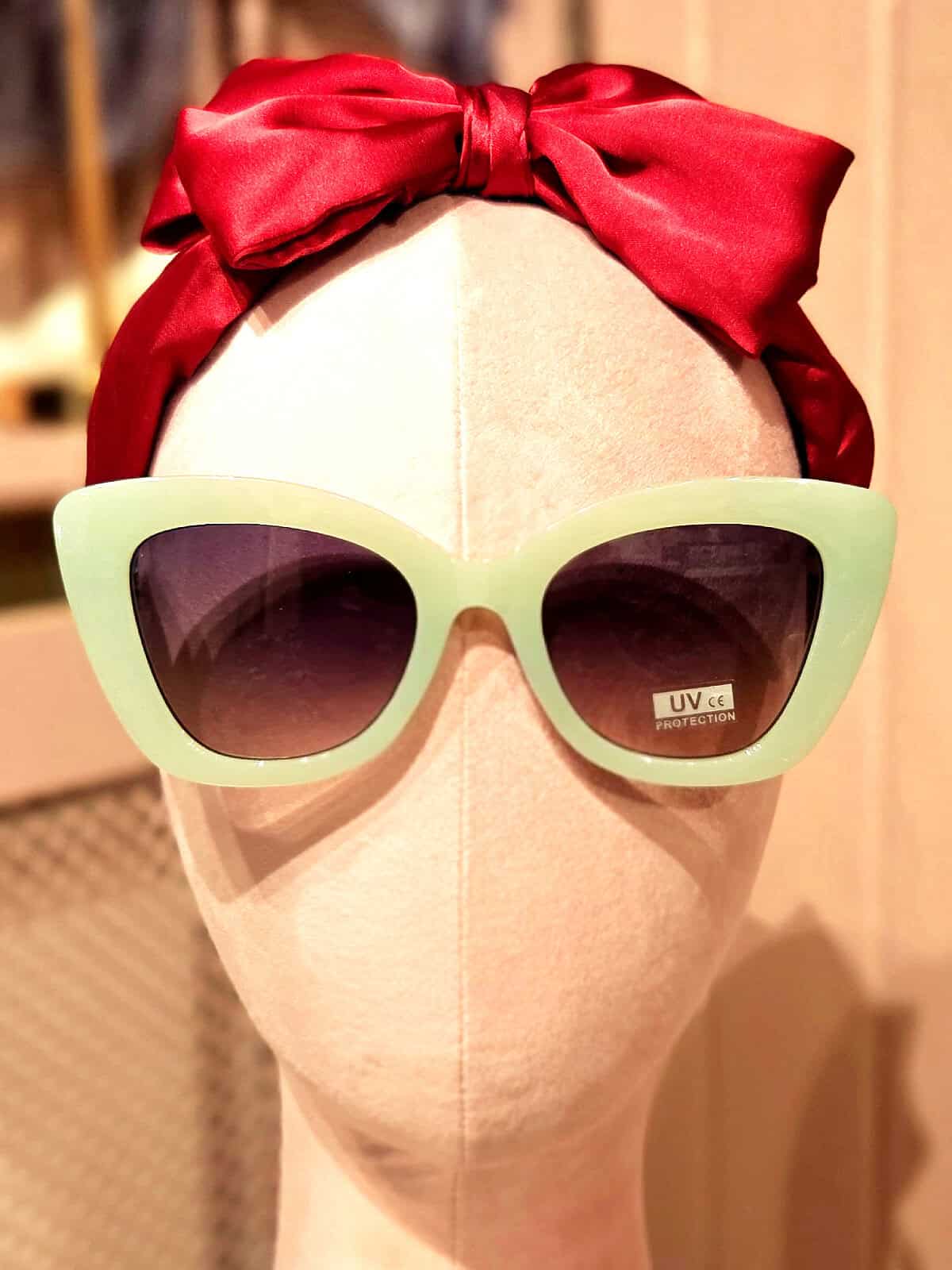 Solbriller med grøn ramme og mørke linser til kvinder.