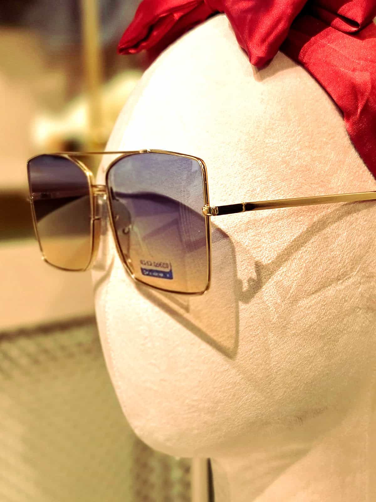 Solbriller med guldramme og blå linser, perfekt til sommerbrug.