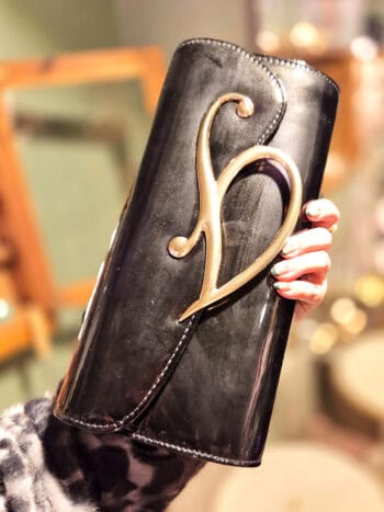 Beskidt clutch i lak med elegant guldlukning, perfekt til festlige anledninger.