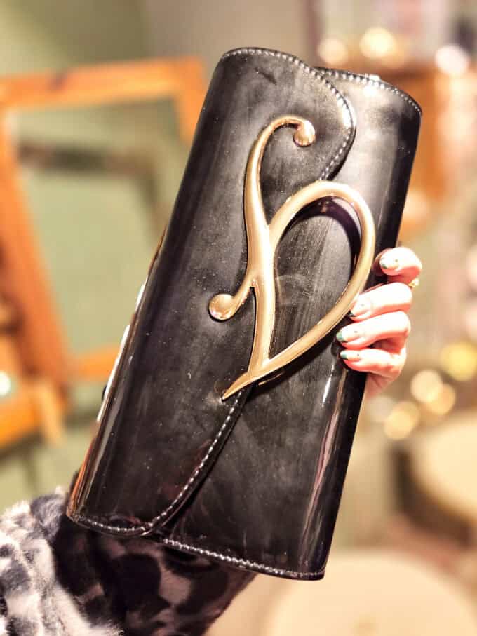 Beskidt clutch i lak med elegant guldlukning, perfekt til festlige anledninger.
