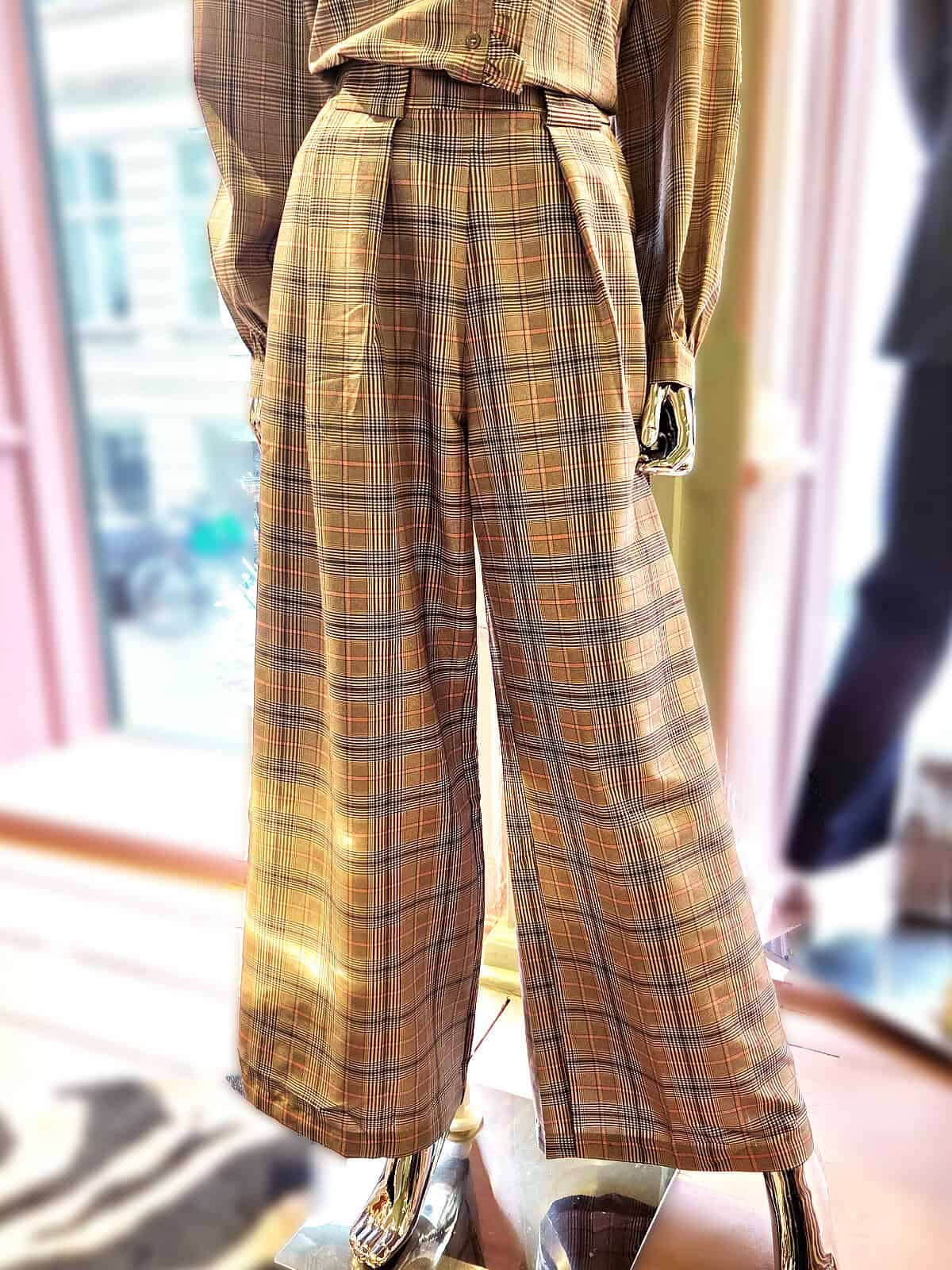 Ternet skjorte med flæser, vist med højtaljede bukser i en butik.