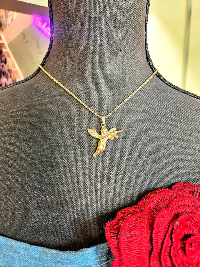 Halskæde med guldbelagt engel med gun vedhæng på sort mannequin, perfekt til accessories.