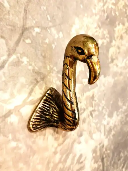 Vægkrog i form af en flamingo i guld, perfekt til dekorative formål.