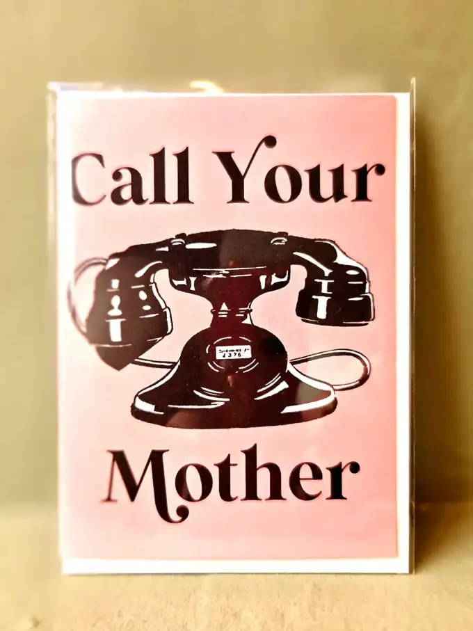 Vintage telefon med teksten "Call Your Mother" i rosa baggrund.