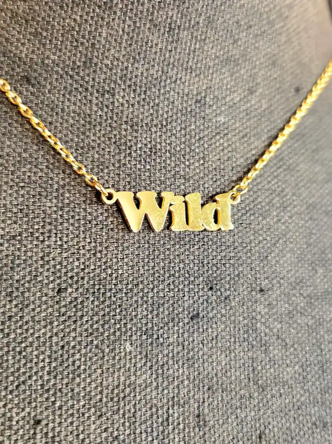 Guld halskæde med "Wild" vedhæng, elegant smykke til kvinder.