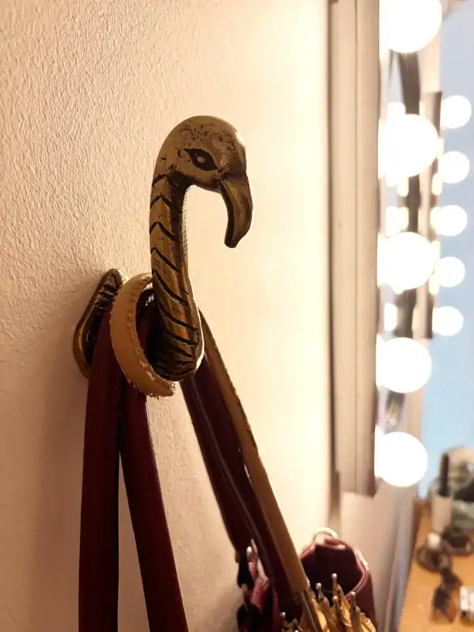 Vægkrog i form af en elegant flamingo i guld, perfekt til at hænge tøj eller accessories.
