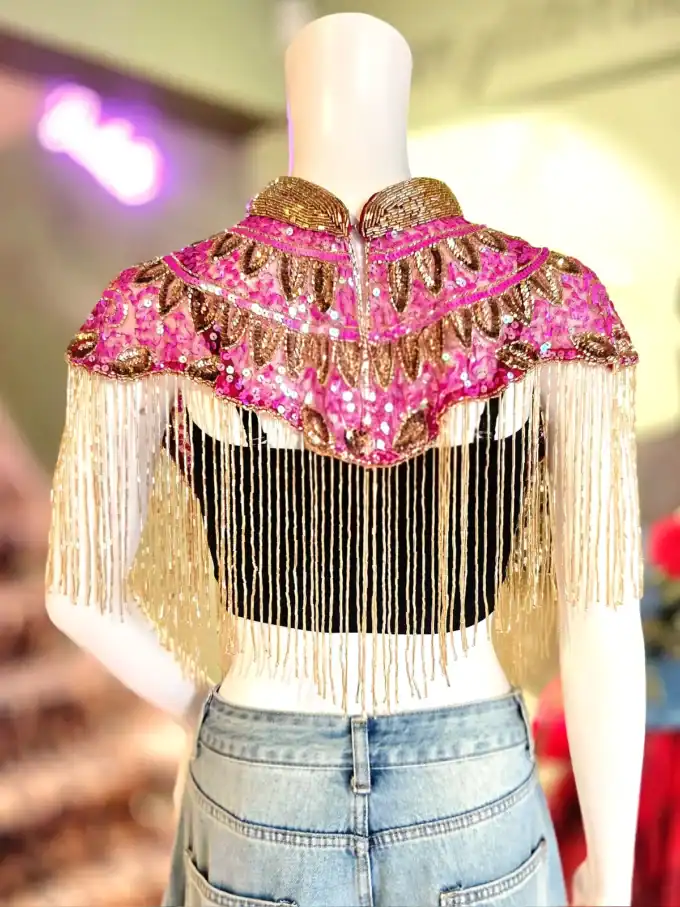 Festlig pink og guld fringed cape med perler og glimmer, perfekt til kostumer og temafester.