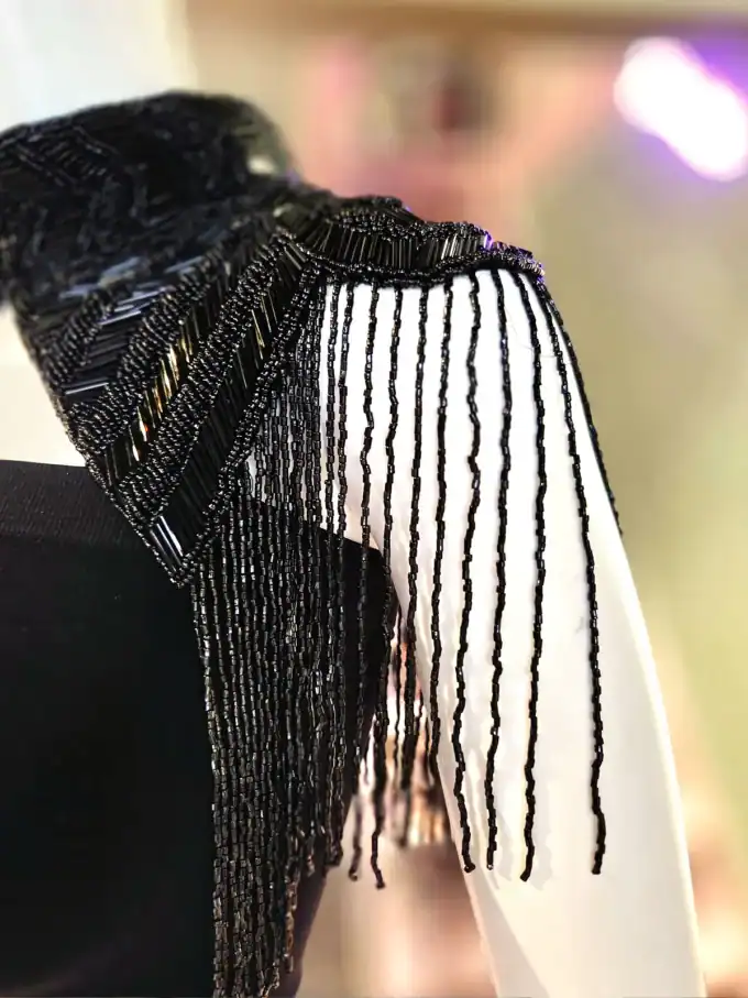 Elegant sort capelet med perler og frynser, perfekt til fest.