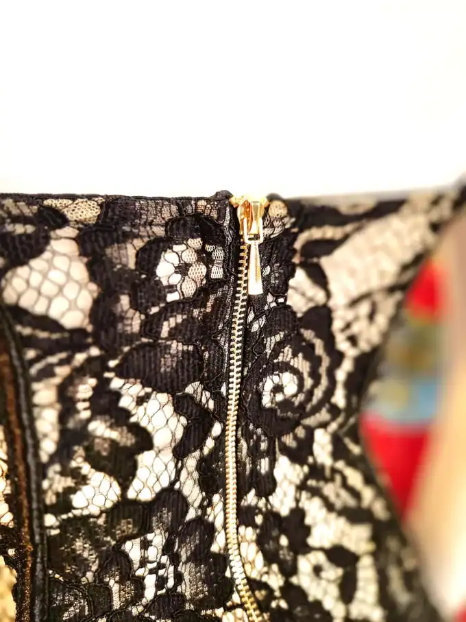 Sort blonde lace corsage top med gylden lynlås, elegant og feminin design.
