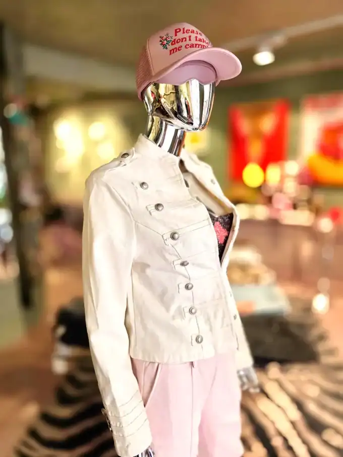 Modell i hvid jakke, pink cap og bukser i et butiksmiljø.