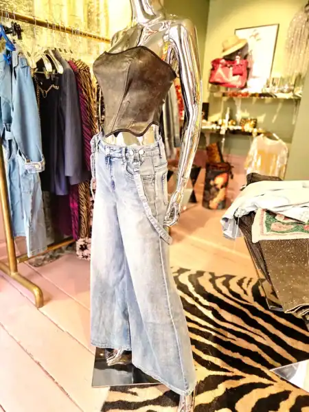 Bredt denim bukser med seler på mannequin i butik.