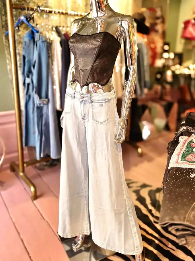 Mode med brede jeans og seler i trendy butiksmiljø.