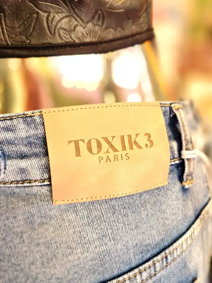 Close-up af denim jeans med Toxik3 Paris label.
