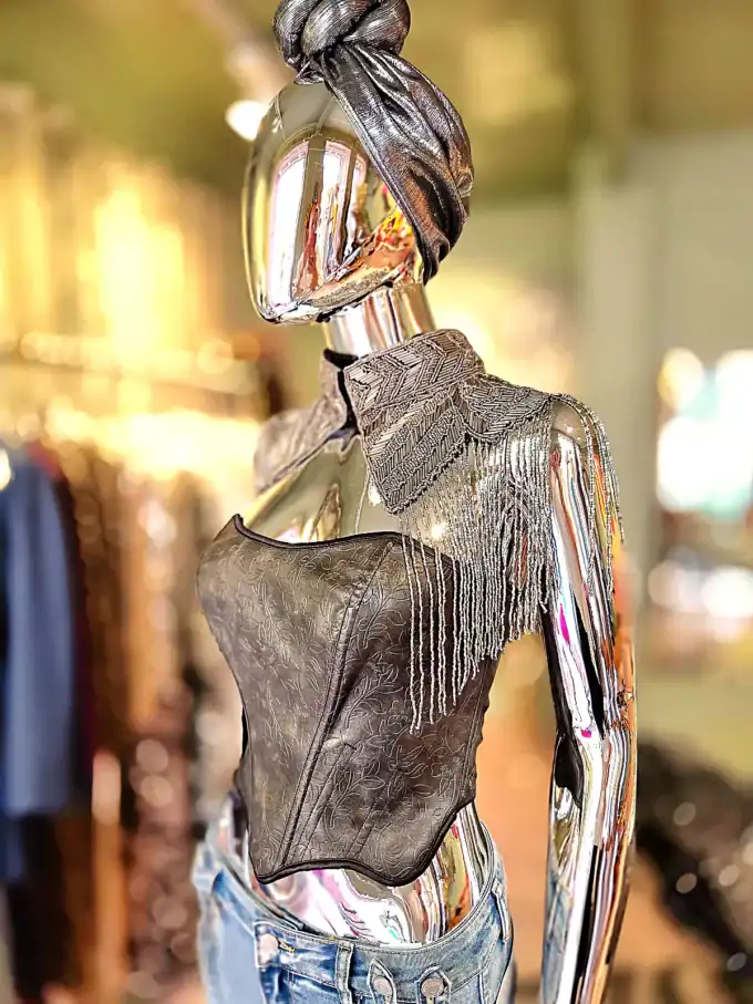 Moderne mannequin med perlekappe og trendy tøj i butiksindretning.
