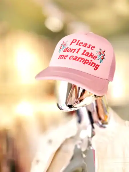 Pink kasket med tekst om camping, på mannequin i butik.