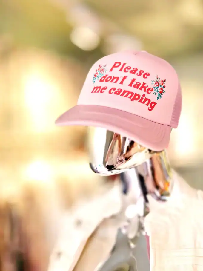 Pink kasket med tekst om camping, på mannequin i butik.