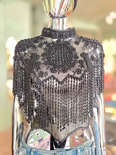 Detaljeret sølvperlekappe med zigzag design og frynser.