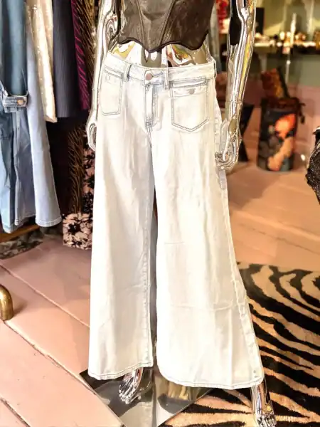 Hvide brede jeans med seler i trendy butiksmiljø.