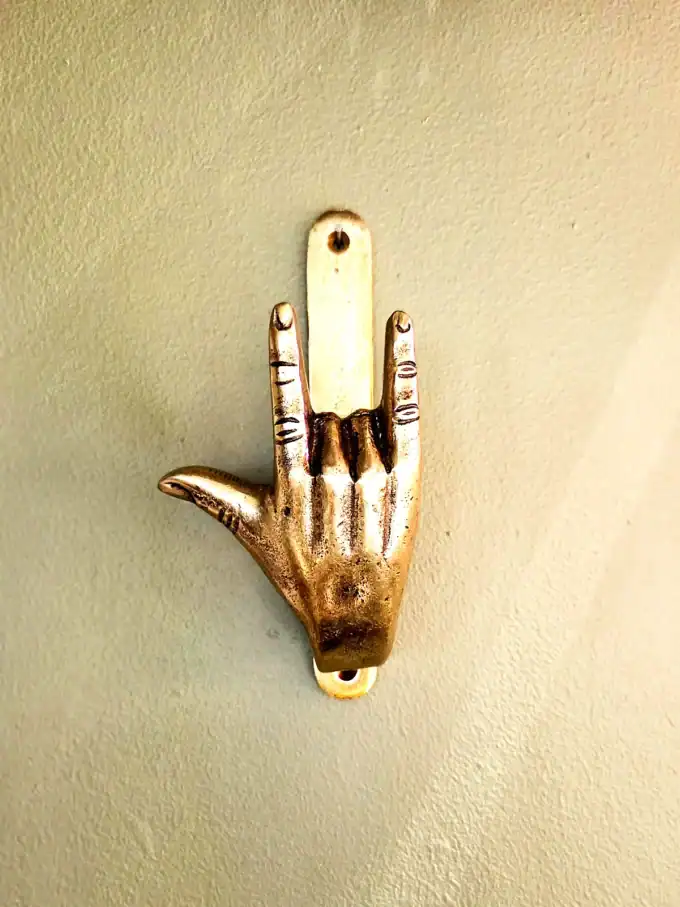 Guld håndtegn i form af en hånd med pegefinger og lillefinger oppe.