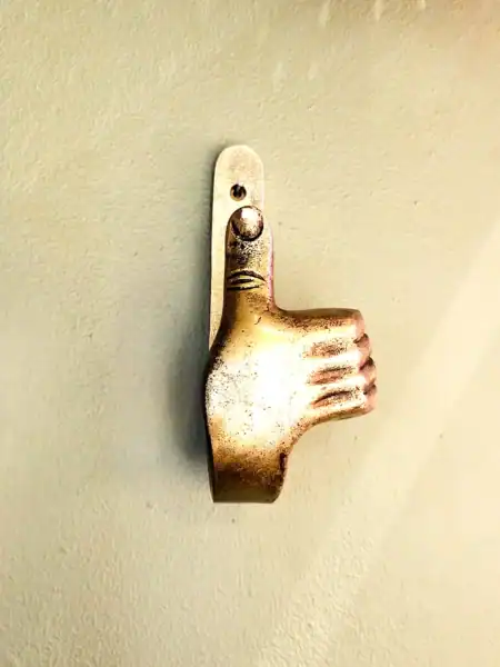 Vægkrog i form af tommelfinger op i sølvfinish.
