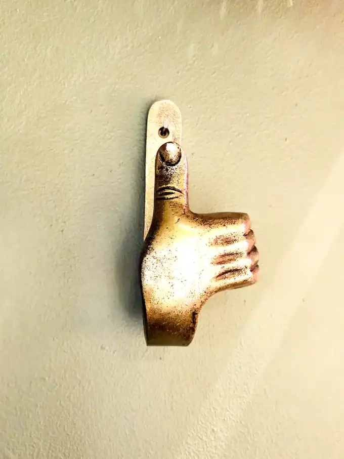 Vægkrog i form af tommelfinger op i sølvfinish.