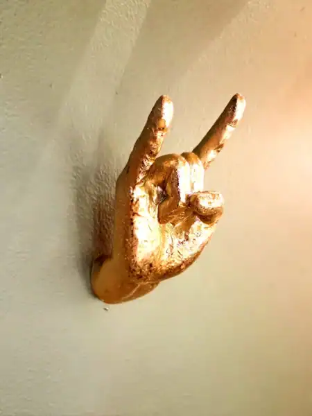 Guld vægkrog formet som en hånd med rock on tegn.