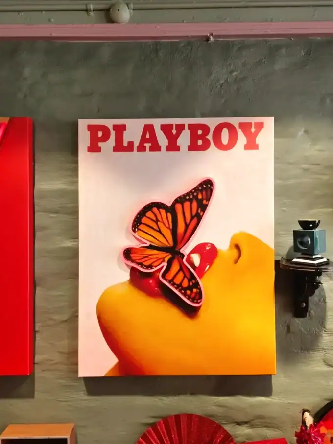 Vægspejl med Playboy-logo og sommerfugl i orange og sort farver.