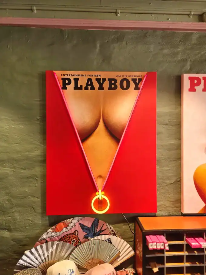Vægspejl med Playboy-omslag, der viser en kvindes bagdel i en gulddel af en medalje.