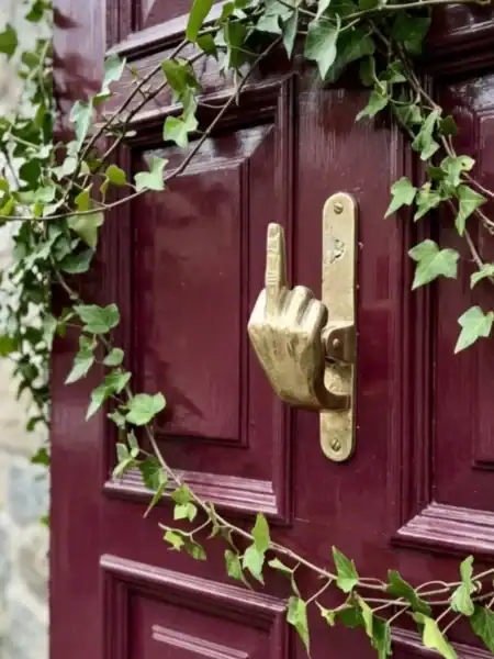 Elegant dørhammer i guld med grønne blade omkring, perfekt til moderne hjem.