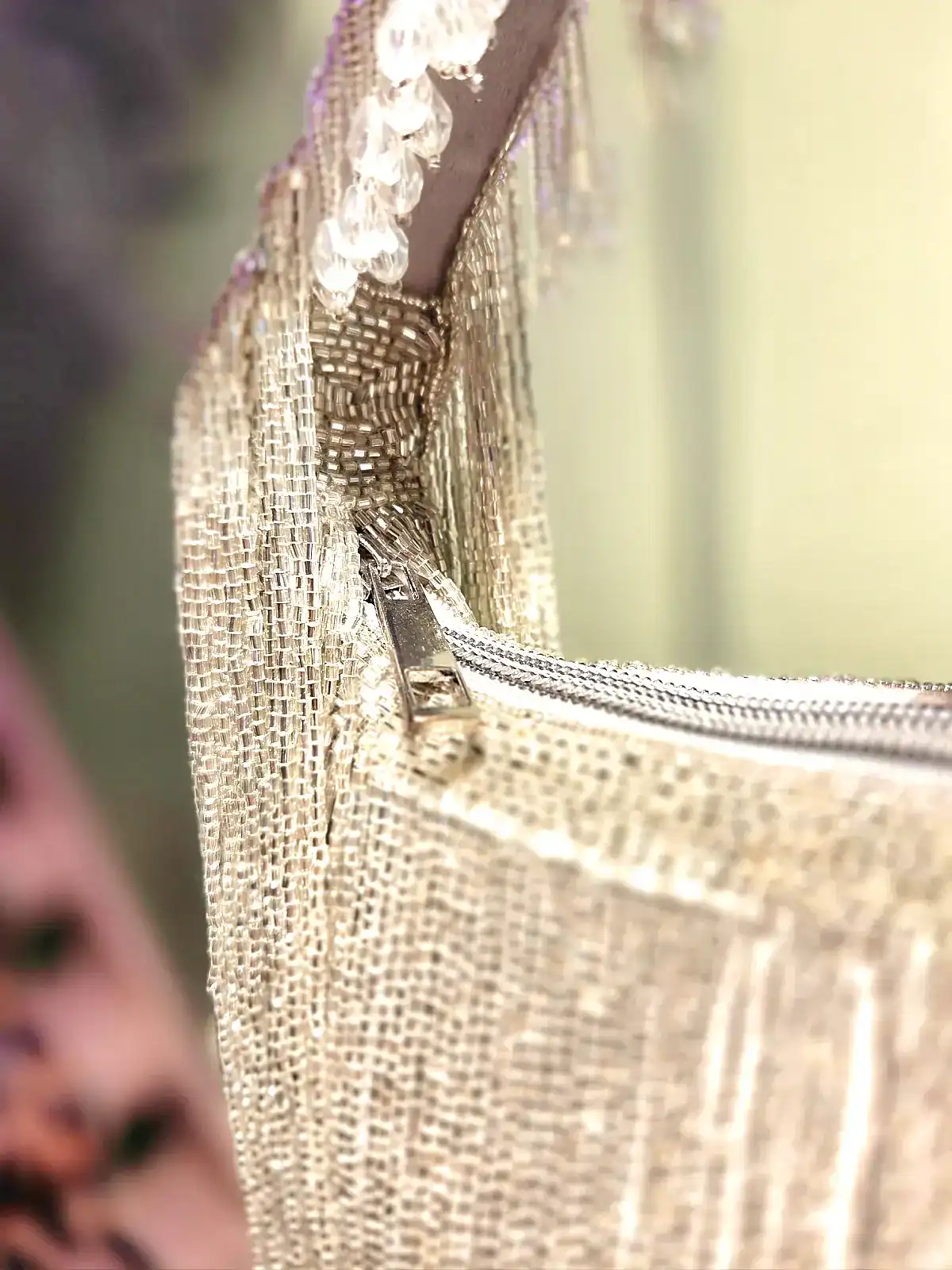 Guld taske med perlefrynser og glat overflade, close-up detalje.