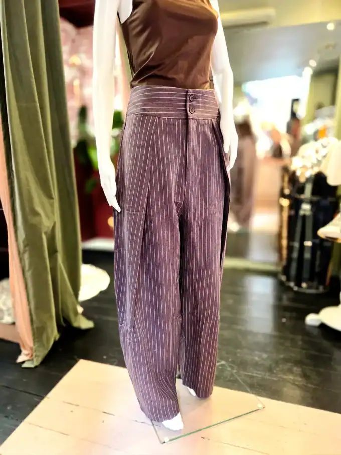 Grå barrelcut bukser med nålestriber i butiksmiljø.