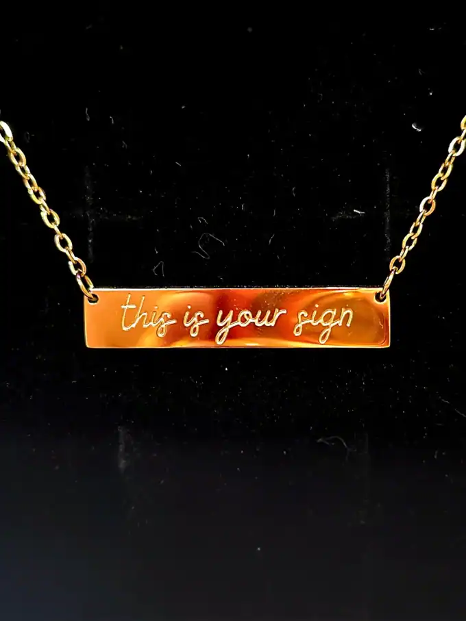 Guldhalskæde med 'this is your sign' tekst, smuk og unik smykke design.