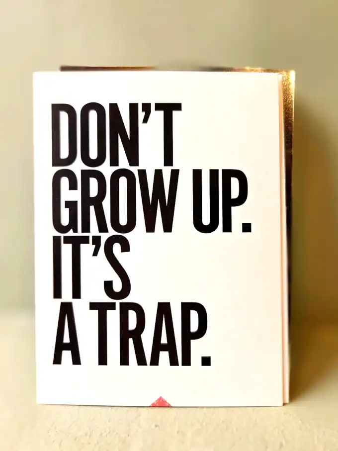 Inspirationskort med citatet 'Don't grow up. It's a trap.'.