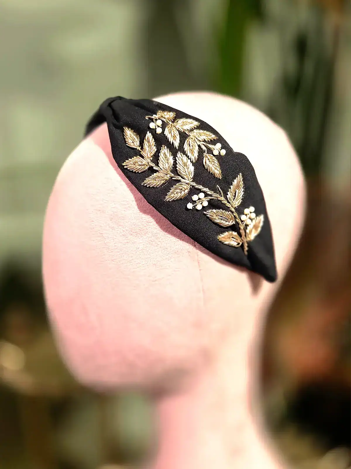 Sort hårbøjle med guld- og perleblomster, perfekt til elegante looks.